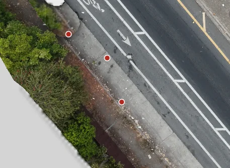 Aerial view of a sidewalk along a bike lane with scattered litter and three red detection markers; no large pile present