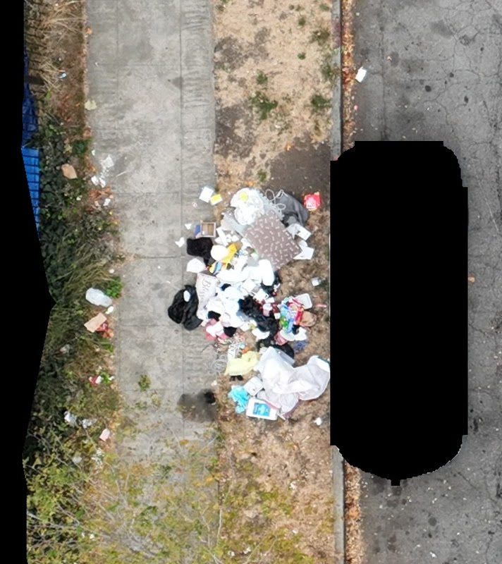 Aerial view of an illegal dumping pile between a sidewalk and a roadway